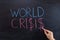 The concept of the world crisis on the blackboard. Hand with chalk