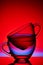 Conceptual composition of two glass teacups over colored red background, close-up, vertical.