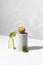 Conceptual creative still life with green fruits and cucumber on concrete podiums on a white background