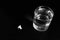 Conceptual glass of water and pills on wooden table in black and