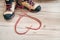 Conceptual image of the pair new trekking boots on the wooden floor background with released long shoelaces behind lying in heart