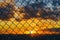 Conceptual image of sunrise sky and steel mesh wire fence.