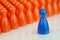 Conceptual orange game pawns and a blue play pawn