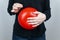 Conceptual photography. The woman holds a red ball near his belly, which symbolizes bloating and flatulence. Then she brings a nee