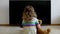 Conceptual portrait. Little girl is sitting on the floor against the black screen of the TV set