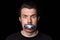 Conceptual portrait of young man with three colors duct tape over his mouth isolated on dark background. Censorship