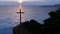 Conceptual religious christian cross standing on rock in the sea