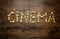 Conceptual shot of word Cinema written by popcorn on wooden back