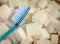 conceptual still life image of toothbrush over massive pile of sugar cubes in dental care and oral hygiene concept as war