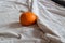 Conceptual still life of a tangerine fruit in an unmade bed showing the concept of wellness and wellbeing