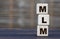 Conceptual word MLM on cubes on a gray blurred background