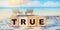 Conceptual word true on wooden cubes on a beautiful ocean beach background. Truth and false concept