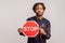 Concerned african guy with dreadlocks holding red stop sign in hands, attention, be careful concept, warning