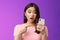 Concerned confused cute young asian woman hold smartphone open mouth, pointing finger telephone, look questioned upset