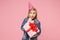 Concerned little kid girl 12-13 years old in denim jacket, birthday hat isolated on pastel pink wall background