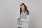 Concerned pensive young woman in gray sweater, scarf putting hand on head on grey wall background in studio