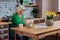 Concerned silver-haired woman in glasses turning recipe book pages