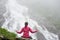 Concerned young female meditating on rock practising yoga in front of spectacular Balea waterfall in Romania.