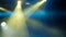 Concert light and smoke. Bright yellow and blue beams of searchlights on the stage. Blurry. Background footage.