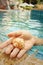 Conch in hand of woman at swimming pool.