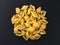 Conchiglie rigate. Raw striped shell pasta on black background, top view
