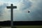 Concrete cross with cloudy sky and helicopter