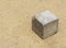 Concrete cube lying on sand ground used by poor kids to play as toy with space for message or object or logo