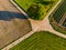 Concrete dirt roads meet between fields at a prominent tree in rural Germany seen by a drone