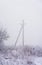 Concrete electric power pole through winter fog