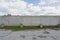 Concrete fence with metal barb construction on blue sky background.