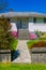 Concrete fence and pathway to the entrance of residential house. Family house with blossoming flowers on the yard in front