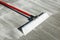 Concrete finishing broom with plastic bristles and red handle