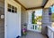 Concrete floor porch of siding house. Flower pot and white entry door.