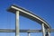 A concrete freeway structure ends abruptly with iron support structures sticking out and safety rails lining the top edge until