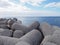 Concrete interlocking tetrapods used to prevent coastal erosion placed on a shoreline with a blue sea and sunny sky