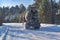 A concrete mixer car drives on a winter forest road, rear view