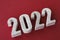 Concrete numbers 2022 on burgundy background. copy space