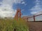 Concrete outdoor bridge with red fences on blue summers sky background.