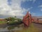 Concrete outdoor bridge with red fences on blue summers sky background over the beach.