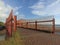 Concrete outdoor bridge with red fences on blue summers sky background over the beach.