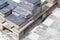 Concrete or paved gray paving slabs or floor or walkway stones stacked on a pallet. Concrete paving slabs in the backyard or road