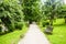 Concrete pavement pathway in the green city park with green trees and empty benches. Garden in urban city in the morning scene in