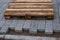 Concrete paver blocks laid beside a building leaving space to the curbstone, a empty wooden pallet is laying on the new paveway