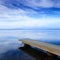 Concrete pier or jetty and on a blue lake and sky reflection on water.