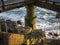 Concrete pillar of wooden jetty with rocks and waves during sunet