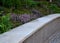 Concrete retaining wall with stone collar builds on purple flowers in flowerbed architectural detail