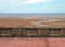 Concrete seawall in blackpool behind the pedestrian walkway with the beach at low tide and calm summer sea with blue sky and c