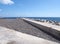 Concrete seawall jetty and breakwater with lighthouse on the beach in funchal madeira with bright sunlit sea and sky
