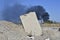 Concrete slab stuck in the ground against the background of a Smoking electrical substation.