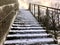 Concrete staircase with snow on steps and rusty handrail